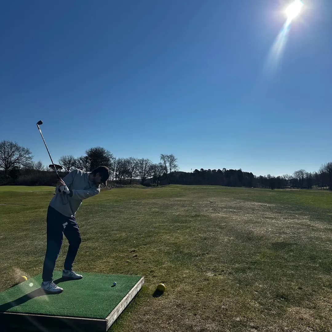 Golfare mitt i svingen på en solig golfbana tidigt på våren