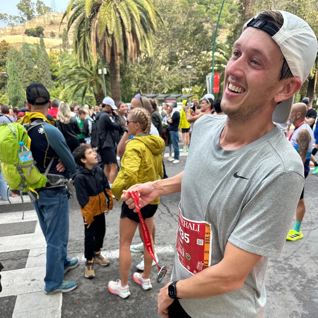 Glad löpare visar upp sin medalj efter ett maratonlopp